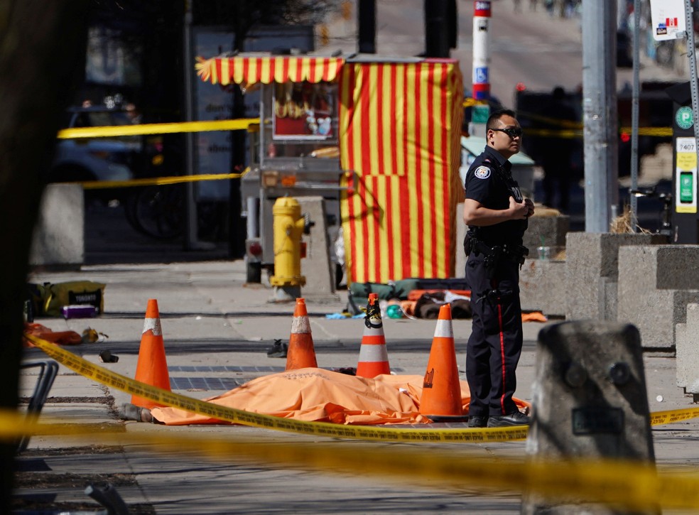 Um policial é visto ao lado de uma vítima no local onde uma van atingiu várias pessoas em Toronto (Foto: Carlo Allegri/Reuters)