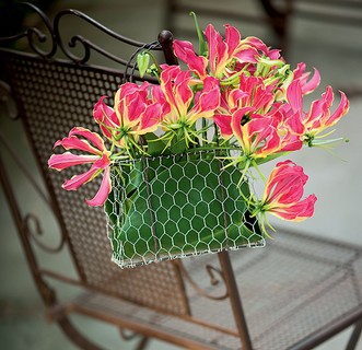 Aqui, a cadeira de ferro ganhou um arranjo criado por Tamako Yoshimoto. As flores estão acomodadas numa bolsinha de tela de galinheiro forrada com folhas