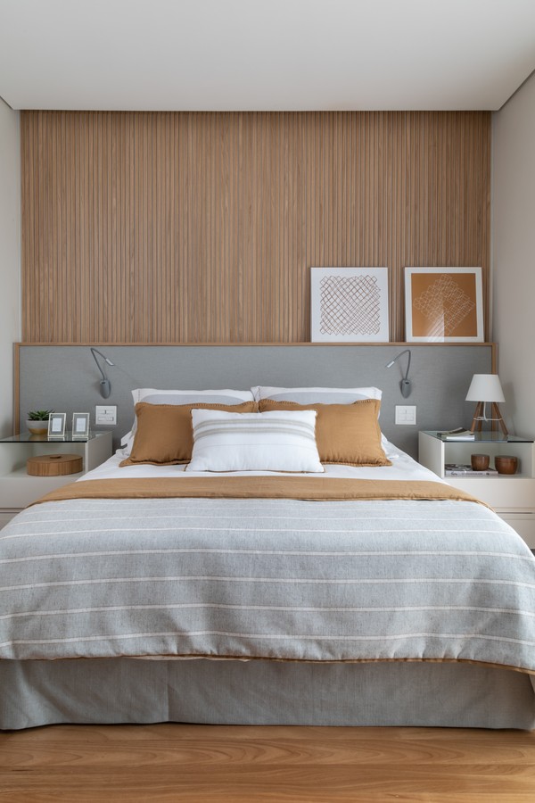 painel de madeira ripada traz textura ao quarto de casal onde predomina cinza e branco 