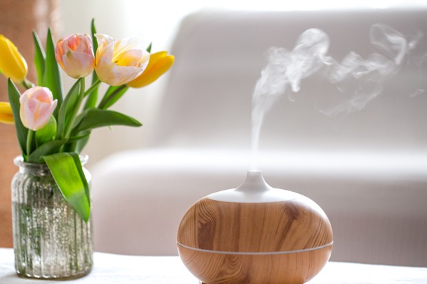 Aroma oil diffuser lamp on the table on a blurred background with a beautiful spring bouquet of tulips. (Foto: Getty Images/iStockphoto)