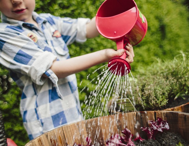 Criança aguando plantas (Foto: Getty Images)