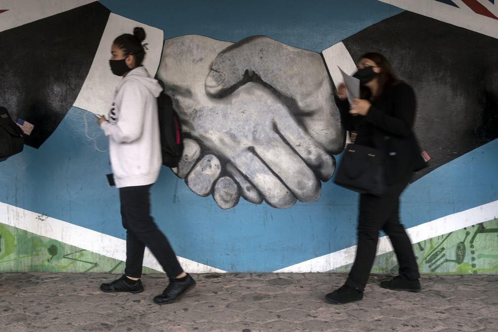 Com máscaras, pessoas autorizadas cruzam a fronteira entre o México e os EUA em Tijuana em 7 de julho — Foto: Guillermo Arias/AFP