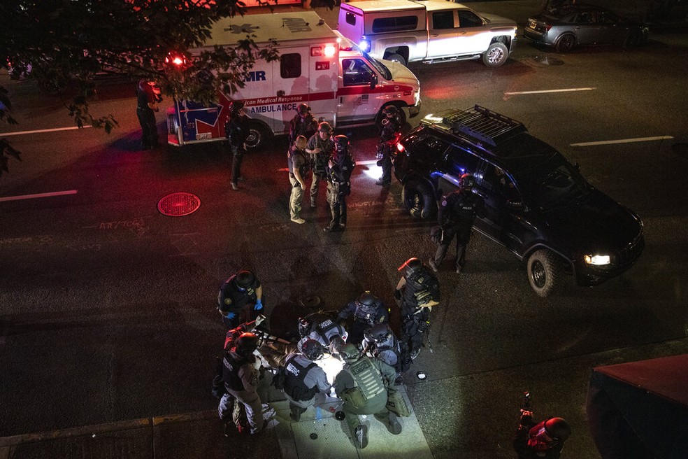 Policiais socorrem homem baleado em Portland, no Oregon, no sábado (29). Ele não resistiu ao ferimento e morreu. — Foto: Paula Bronstein/AP Photo