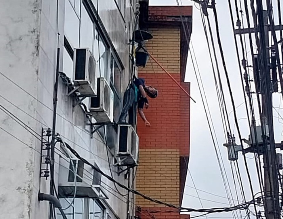 Homem sofre descarga elétrica, desmaia e fica pendurado em prédio em Santos — Foto: Simone de Abreu Teixeira 