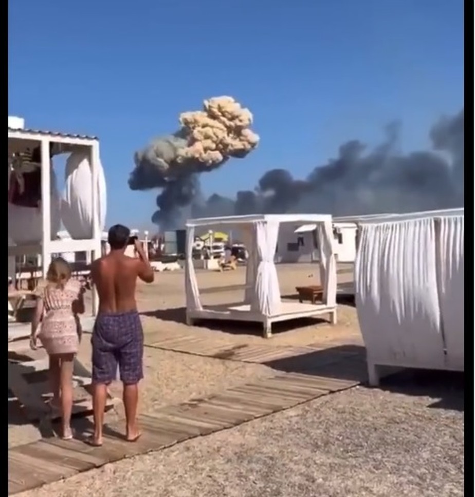 Banhistas observam coluna de fumaça após explosões na base de Novofeodorivka, na Crimeia