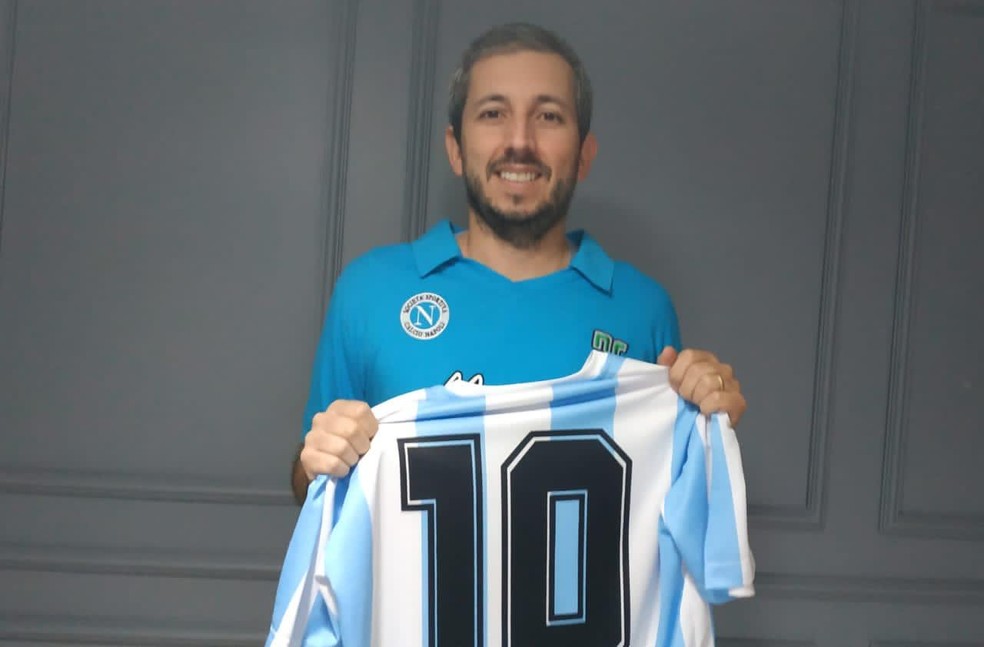 Analista de dados Délio Mendes segura camisa da seleção argentina; ele esteve no jogo entre Brasil e Maradona, em 2006, no DF — Foto: Arquivo pessoal