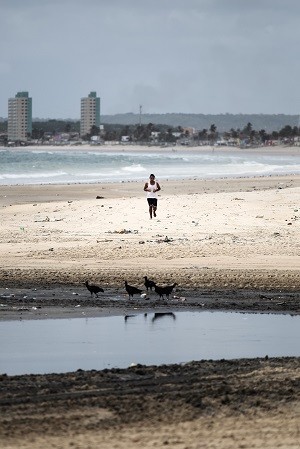Homem se exercita na praia da Avenida, local onde é despejada a água que percorre pelo Salgadinho (Foto: Jonathan Lins/G1)