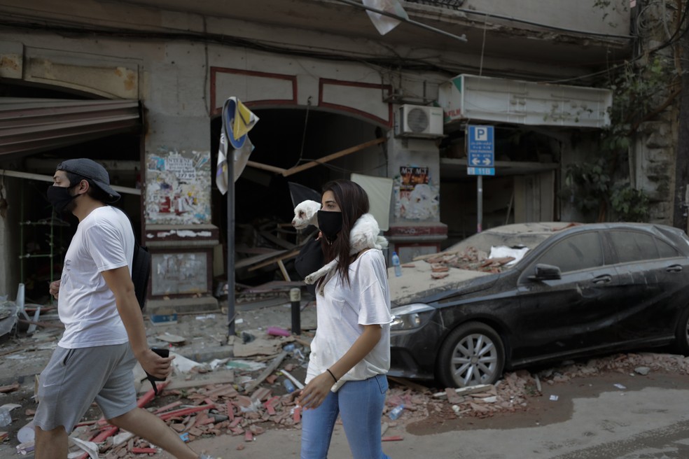 5 de agosto - Pessoas passam por prédios danificados após explosão em Beirute, Líbano — Foto: Hassan Ammar/AP