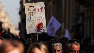 Manifestante segura um cartaz com a palavra "desprezo" e a caricatura de Emmanuel Macron enquanto marcha contra a reforma da Previdência — Foto: Thibaud Moritz/AFP