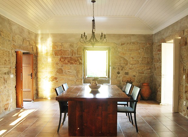 Sala de jantar da casa principal. Uma das fortes características desse projeto são as rústicas paredes de granito, preservadas da obra original (Foto: Divulgação)