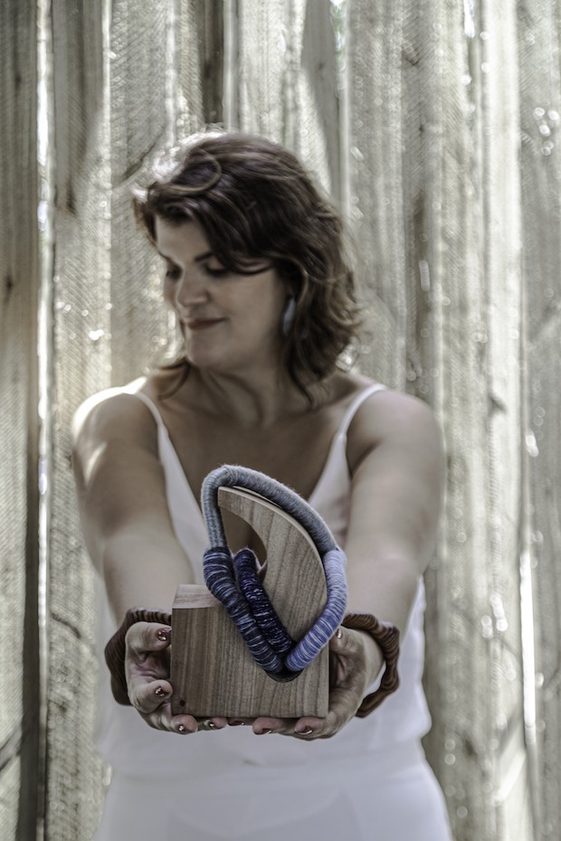 Juliana Pippi segura a peça “Onda” – Madeira de garimpo jequitibá e tecelagem manual (18A x 11,5P x 11,5L) (Foto: Gabriela Daltro / Divulgação)