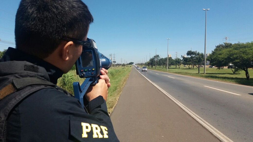Policial da PRF usa radar para fiscalizar velocidade de veículos em trecho da BR-060, no DF, em imagem de arquivo — Foto: PRF/Divulgação