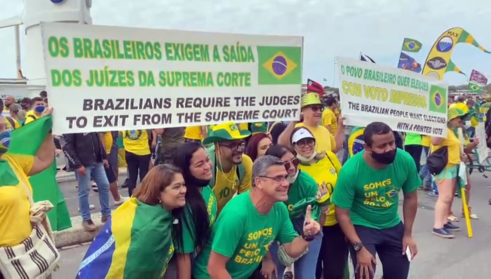 Manifestantes sem máscara posam diante de faixa contra o STF — Foto: TV Globo