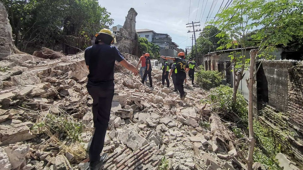 Socorristas caminham sobre os destroços em Vigan, província de Ilocos Sur, nas Filipinas, após terremoto — Foto: Bureau of Fire Protection via AP Photo