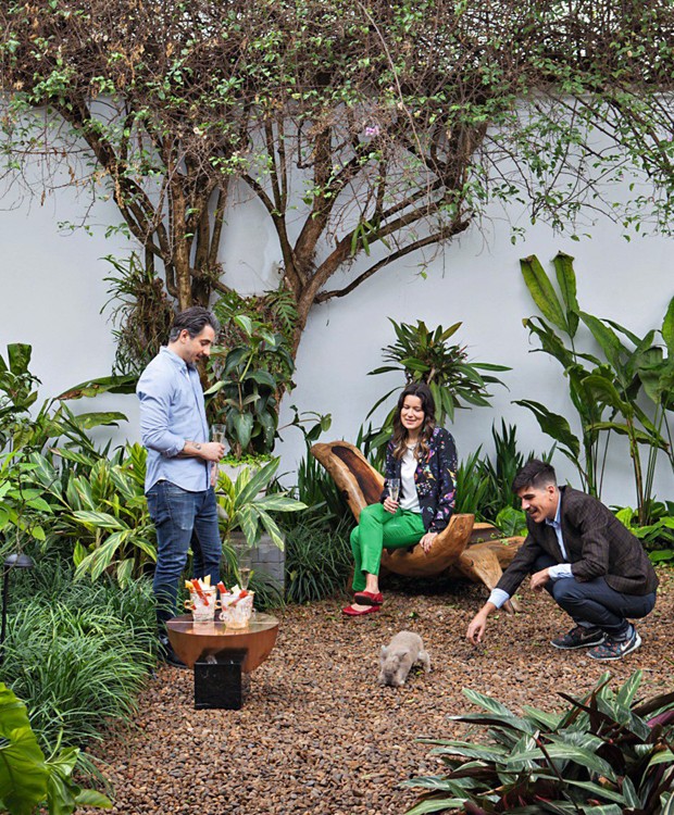 O convidado Conrado Colnaghi (de pé), Vivian e André brincam com o coelho Alfredo no jardim cheio de verde da casa modernista (Foto: Lufe Gomes / Editora Globo)