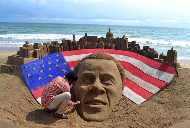 Artista retoca escultura de Obama em praia na Índia (Foto: AFP)