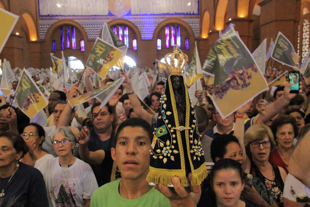 Fiel adolescente segura imagem de Nossa Senhora Aparecida na principal missa do dia