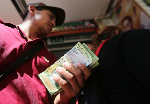 Homem segura notas de bolívares em Caracas, na Venezuela (Foto: Mario Tama/Getty Images)