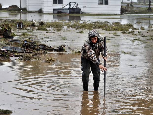 Homem limpa sua propriedade em uma área inundada em Hygeine, Colorado. Buscas continuam por pessoas desaparecidas em locais isolados no estado. (Foto: Brennan Linsley/AP)