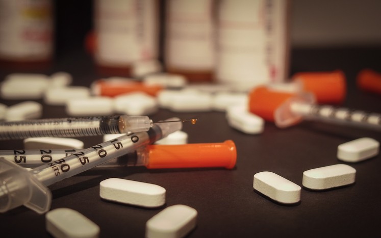 An used syringe is discarded while prescription medication is strewn about haphazardly. (Foto: Getty Images/iStockphoto)