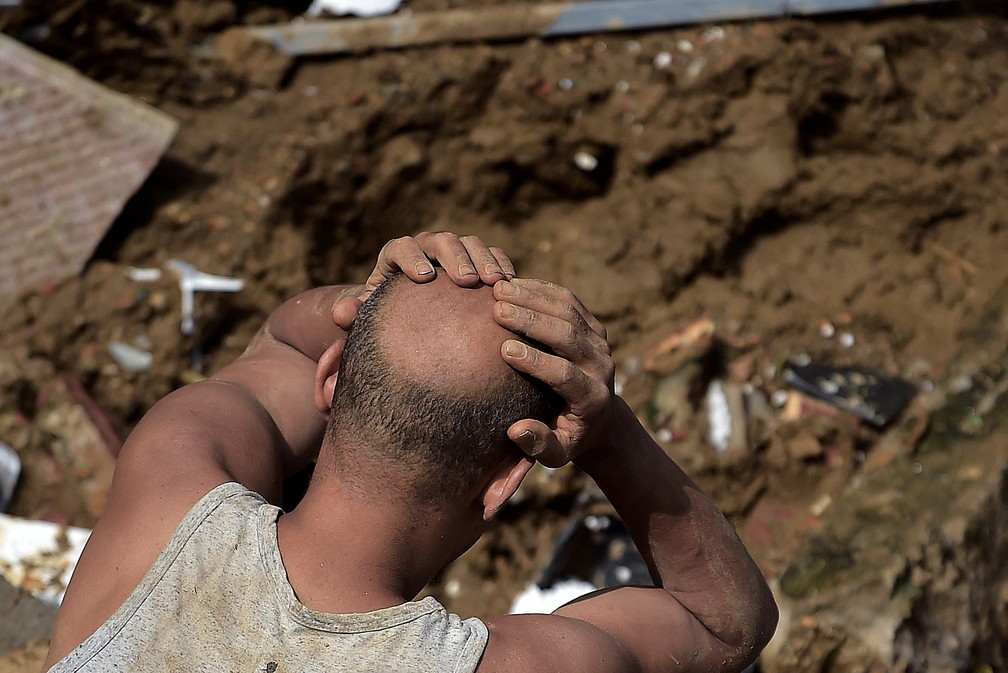 Homem leva as mãos à cabeça durante a busca por sobreviventes após deslizamento no Morro da Oficina, em Petrópolis (RJ) — Foto: Carl de Souza/AFP