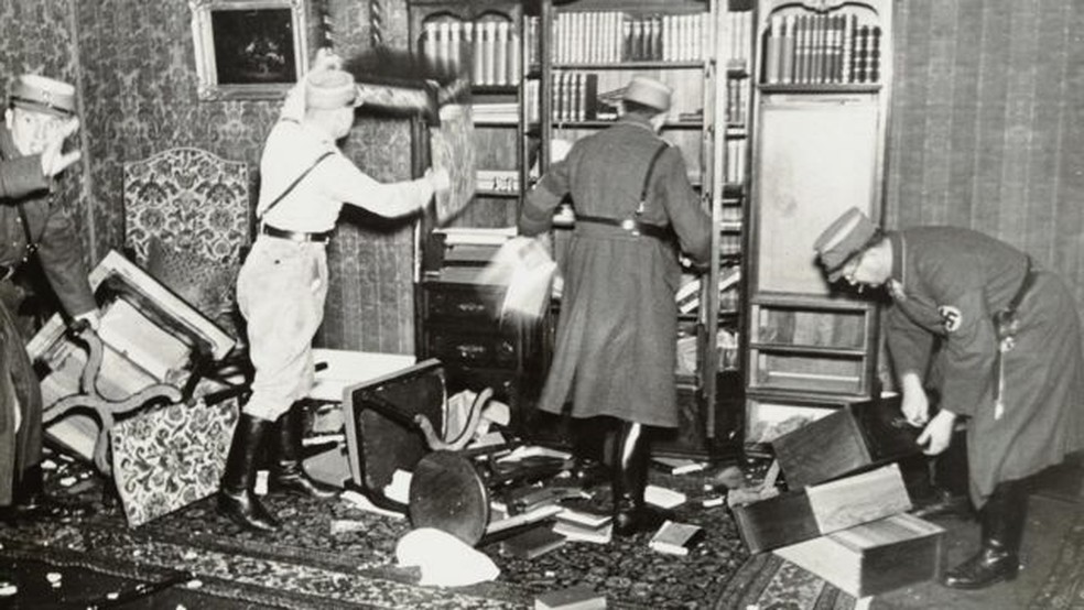 Oficiais nazistas derrubando livros de uma estante — Foto: YAD VASHEM PHOTO ARCHIVE/via BBC