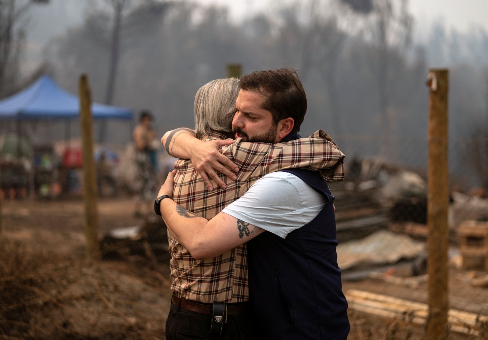 Presidente Chileno Gabriel Boric abraça morador de Huallerehue, área devastada por incêndios — Foto: AFP