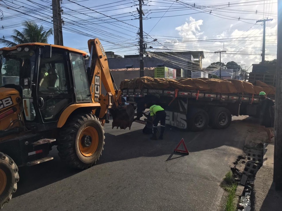 Trator auxilia retirada de caminhão que caiu em buraco em Natal — Foto: Kleber Teixeira/Inter TV Cabugi