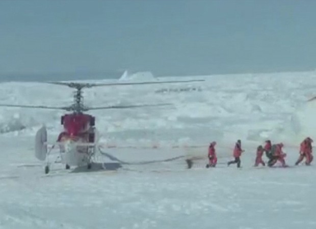 Equipe de resgate deixa helicóptero para verificar condições de saída de navio no gelo (Foto: Chris Turney/Reuters)