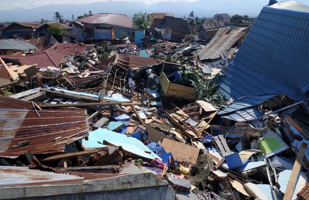 Pessoas procuram objetos pessoas nos destroços de casas em uma área residencial de Palu, na Indonésia, após terremoto e tsunami no sábado (30) — Foto: Darwin Fatir/Antara Foto/via reuters