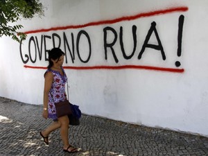 Mulher passa em frente a muro com frase de protesto contra o governo, em Lisboa (Foto: Reuters)