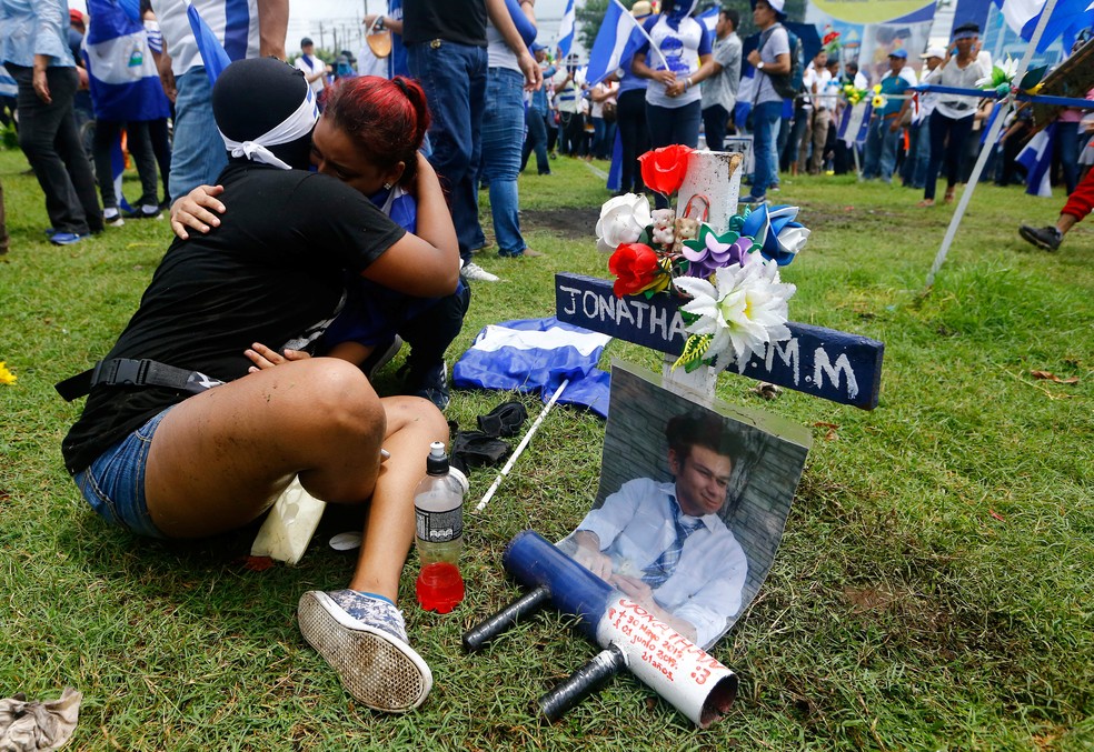 Manifestantes se abraçam perto de memorial ao estudante universitário Jonathan Morales durante protesto contra o presidente Daniel Ortega em Manágua, na Nicarágua (Foto: Oswaldo Rivas/Reuters)