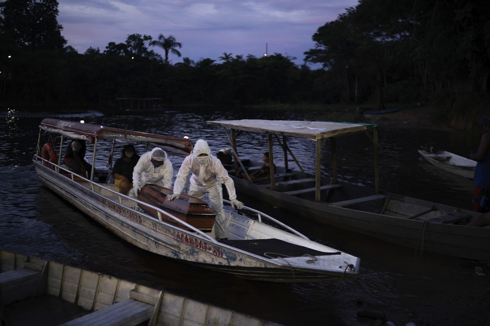 Funcionários da SOS Funeral transportam em barco caixão de vítima suspeita de Covid-19 no Rio Negro, no Amazonas, no dia 14 de maio. — Foto: Felipe Dana/AP