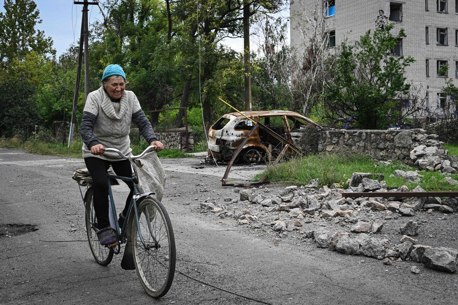 Mulher anda de bicicleta ao lado de um hospital local fortemente danificado na aldeia de Vysokopillya, Kherson