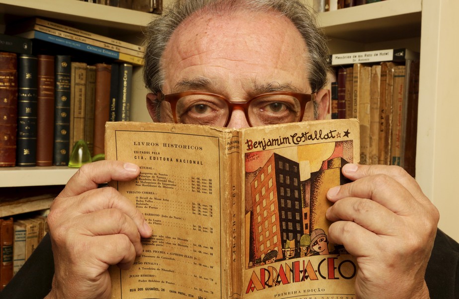 Ruy Castro com uma edição antiga de 'Arranha-céu', de Benjamim Costallat
