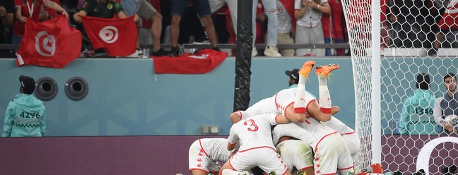 Jogadores da Tunísia se jogam em cima do atacante Wahbi Khazri autor do primeiro gol da partida — Foto: FRANCK FIPE/AFP