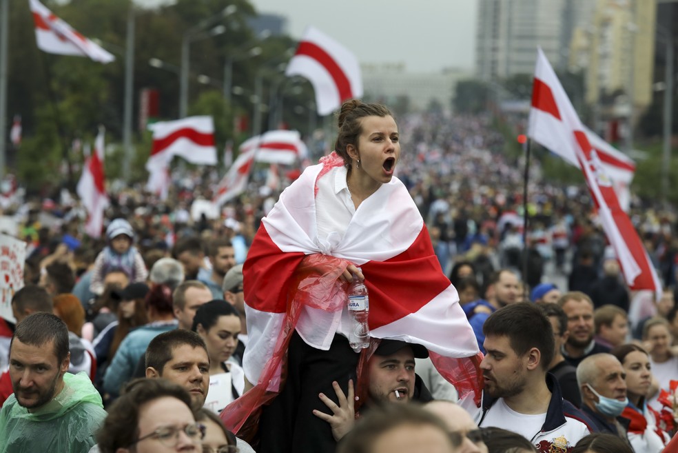 Mulher se cobre com a antiga bandeira de Belarus — Foto: Associated Press