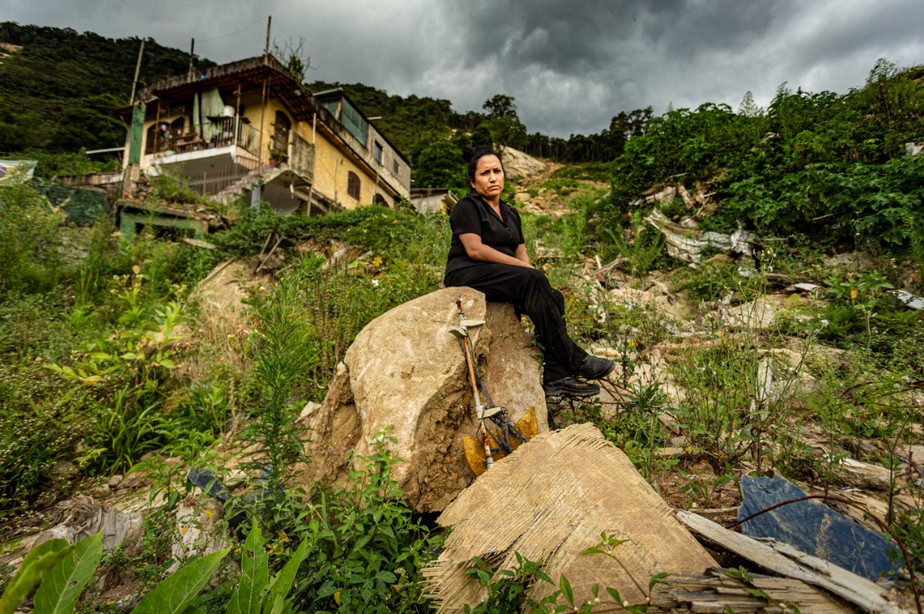 Cristiane Gross sentada na pedra onde ficava sua casa, destruída na tragédia no Morro da Oficina. Moradores lamentaram decisão da Justiça.