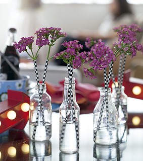Garrafas transparentes viram vasos de efeito com essa ideia fácil de ser executada: espete as flores em canudinhos estampados