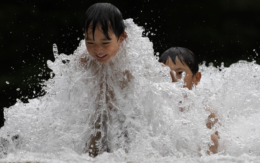 Crianças brincam em uma fonte de água em Tóquio, no Japão. (Foto: Shizuo Kambayashi/AP)