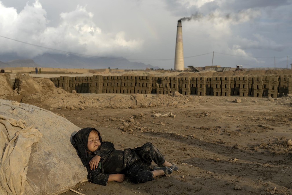 Criança descansa em fábrica de tijolos em Cabul, no Afeganistão. — Foto: Ebrahim Noorozi/ AP 