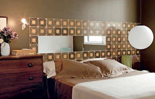 A cabeceira da casa do designer de interiores Sandro Brasil tem azulejos modernistas – no meio deles, há um espelho. Na cômoda, famosa luminária de Ingo Maurer