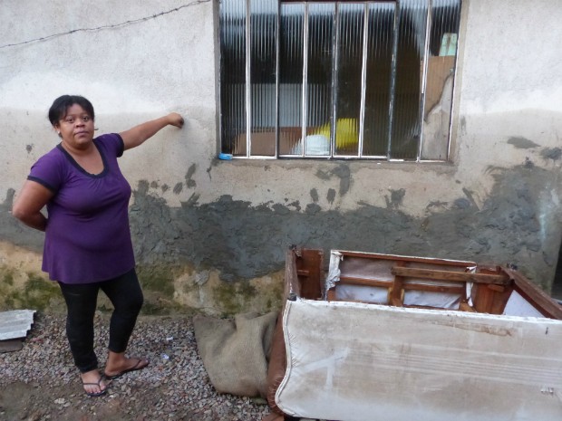 Márcia Assis Soares do Nascimento, moradora da Cidade Industrial de Curiti aponta o ponto que enchente atingiu a casa onde vive com a família (Foto: Thais Kaniak / G1 PR)