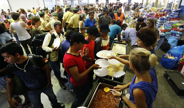Voluntários servem refeição para os refugiados que chegam à estação de Munique, na Alemanha  (Foto: Matthias Schrader/ AP)