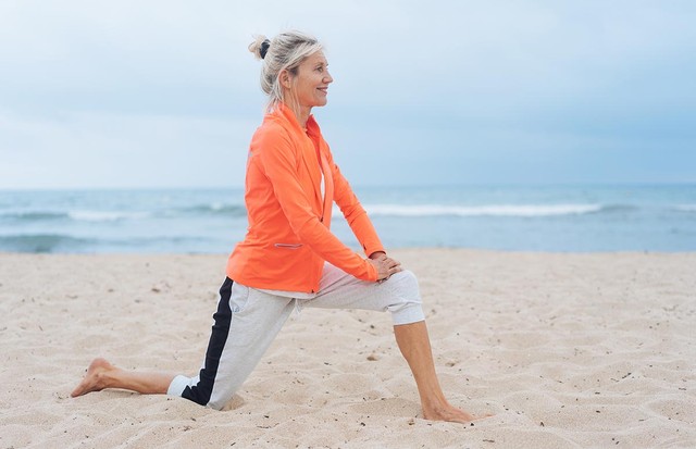 Active healthy blond woman doing stretching exercises on a sandy tropical beach on a hazy day in a close up profile view (Foto: Getty Images/iStockphoto)