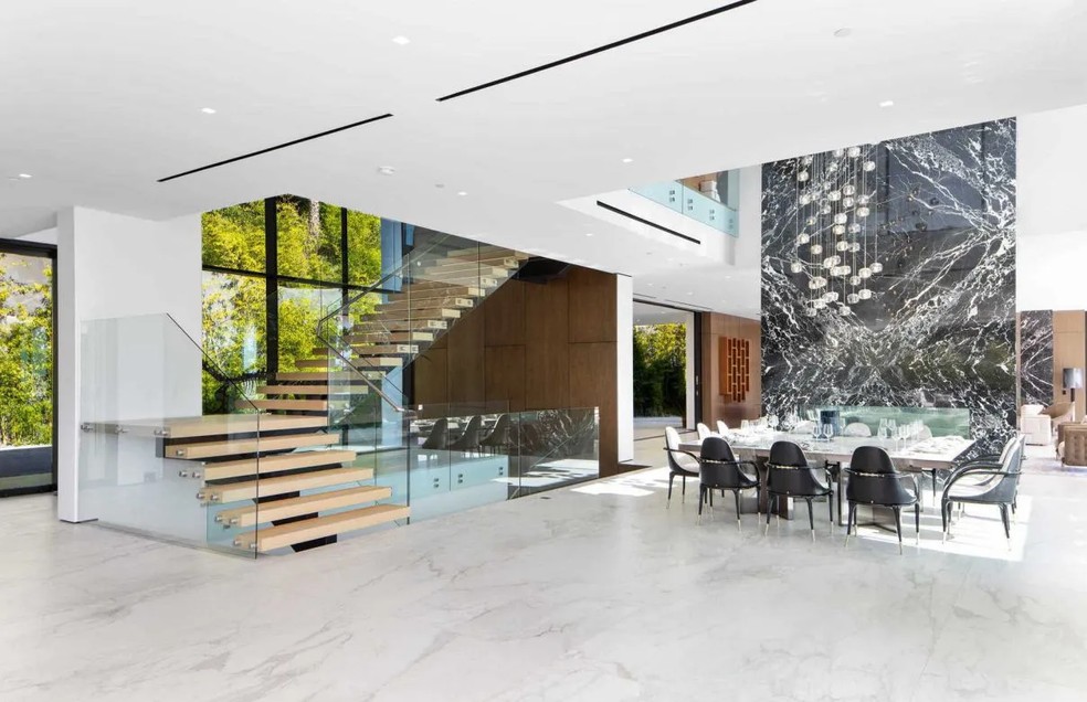 Uma parede gigante de mármore preto com ranhuras brancas marca o pé-direito duplo na sala de jantar — Foto: Antonio Barcelo / theagencyre.com / Reprodução