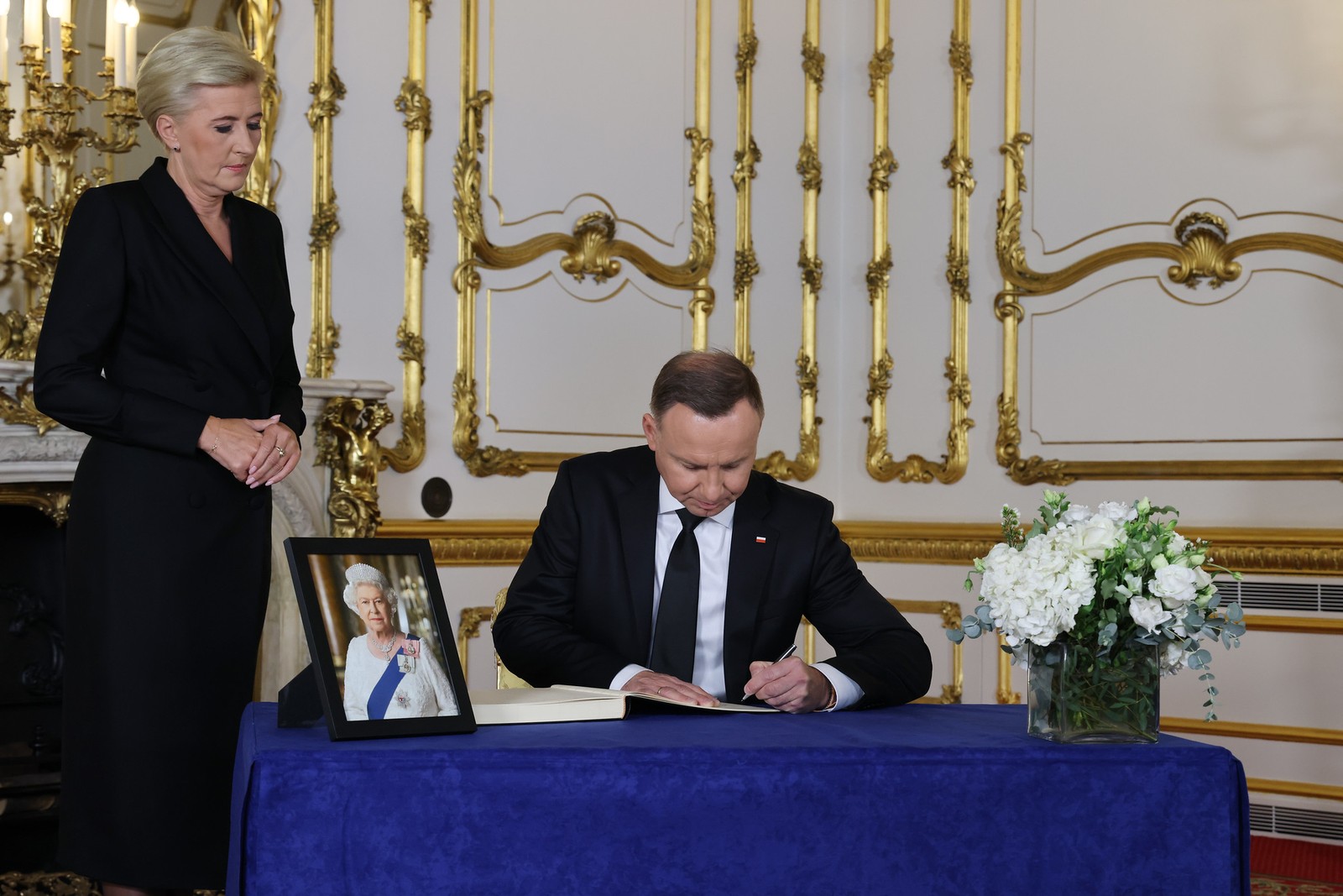 Andrzej Duda, presidente da Polônia, assina o livro de condolências acompanhado da primeira-dama Agata Kornhauser-Duda — Foto: Rory Arnold