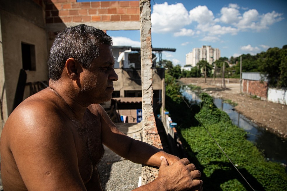 Do terraço de sua casa, Luiz Alberto avista a poluição do córrego que corta sua rua, em São Gonçalo — Foto: Hermes de Paula/Agência O Globo