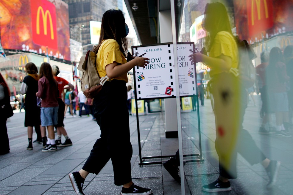 Mulher entra em loja ao lado de uma placa anunciando vagas de emprego na Times Square em Nova York, EUA — Foto: Eduardo Munoz/Reuters