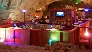 Acomodação busca recriar uma atmosfera caseira, com uma estante repleta de livros, televisão, dois sofás, uma poltrona, confortáveis camas — Foto: Divulgação/Grand Canyon Caverns